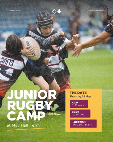 Children playing rugby during a junior camp on a grassy field.